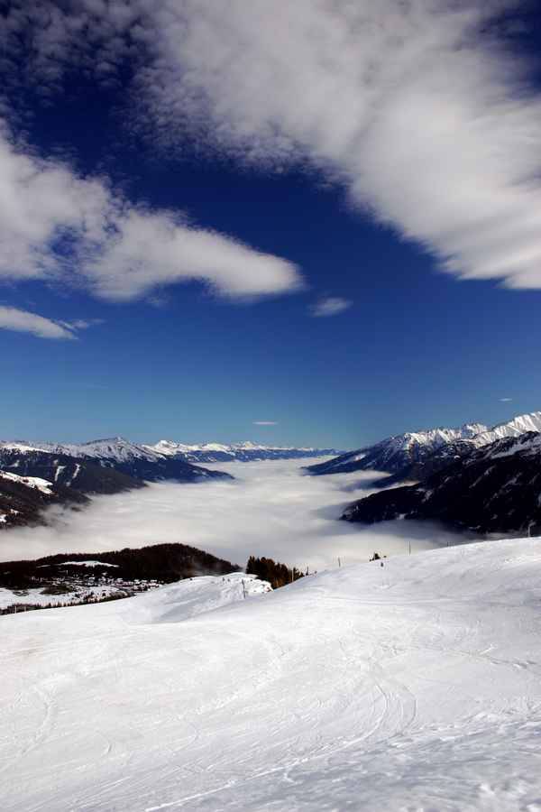 Blick vom Berg über die Skipiste ins vernebelte Tal