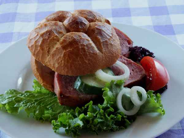 Leberkäsesemmel auf Teller mit Salat,Tomate und Zwiebeln
