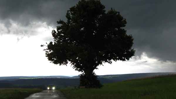 Dunkle Wolken mit PKW und Baum