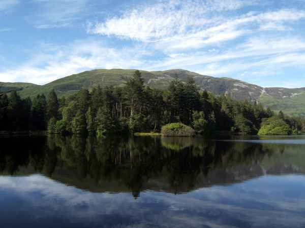 Berg & Waldlandschaft vor blauem See in Großbritannien