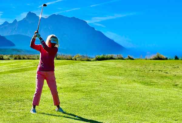 Golferin auf dem Fairways vor Bergen