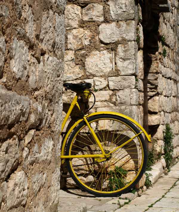 gelbes Fahrrad lehnt an Steinmauer