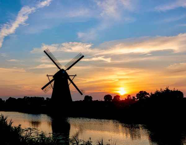 Windm&uuml;hle am Fluss mit sonnenuntergang