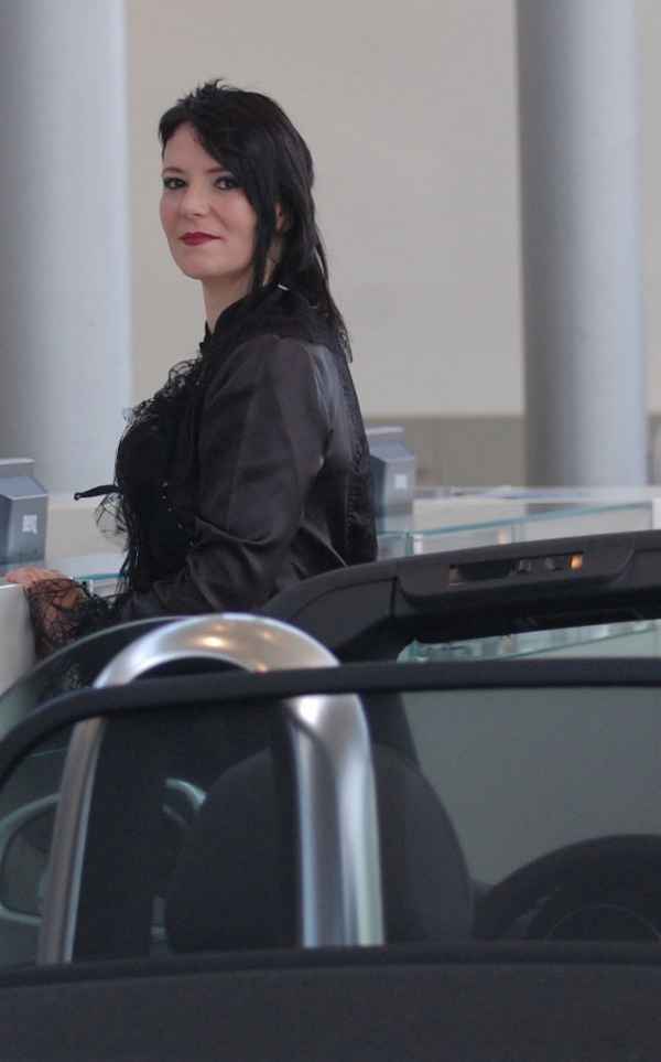 Sie steht an der Kasse und lächelt.