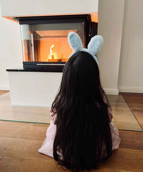 Vor dem Kamin sitzendes M&auml;dchen