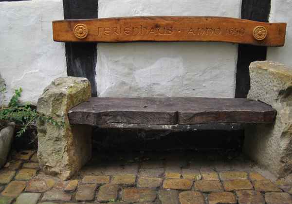 Holz-und Steinbank, vor einem Fachwerkhaus