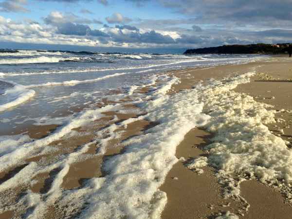 Schaumbewölkter Sandstrand auf Rügen