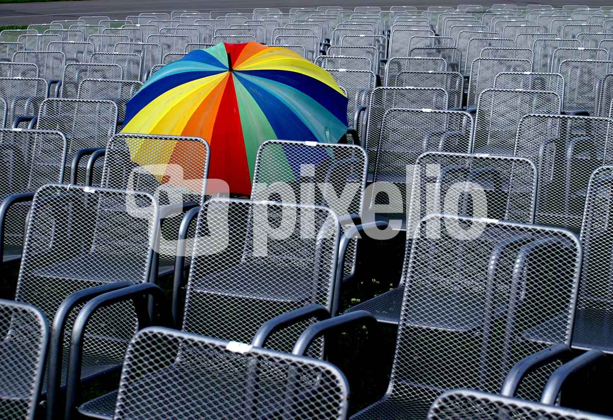 leere Stuhlreihen mit buntem Schirm