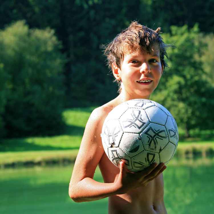 Junge am Badesee mit Ball
