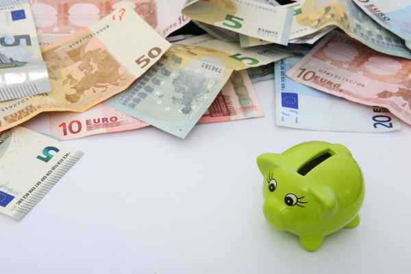 Sparschwein vor Geldhaufen