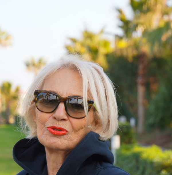 blonde Seniorin unter Palmen 1