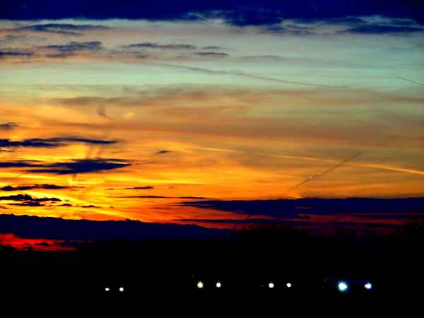 Scheinwerfer auf Landstrasse im Sonnenuntergang
