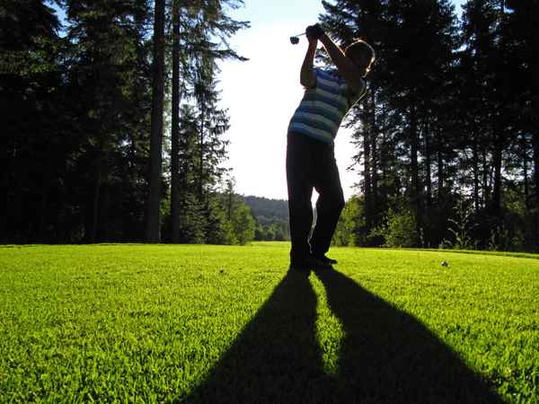 Golfer beim Abschlag im Gegenlicht