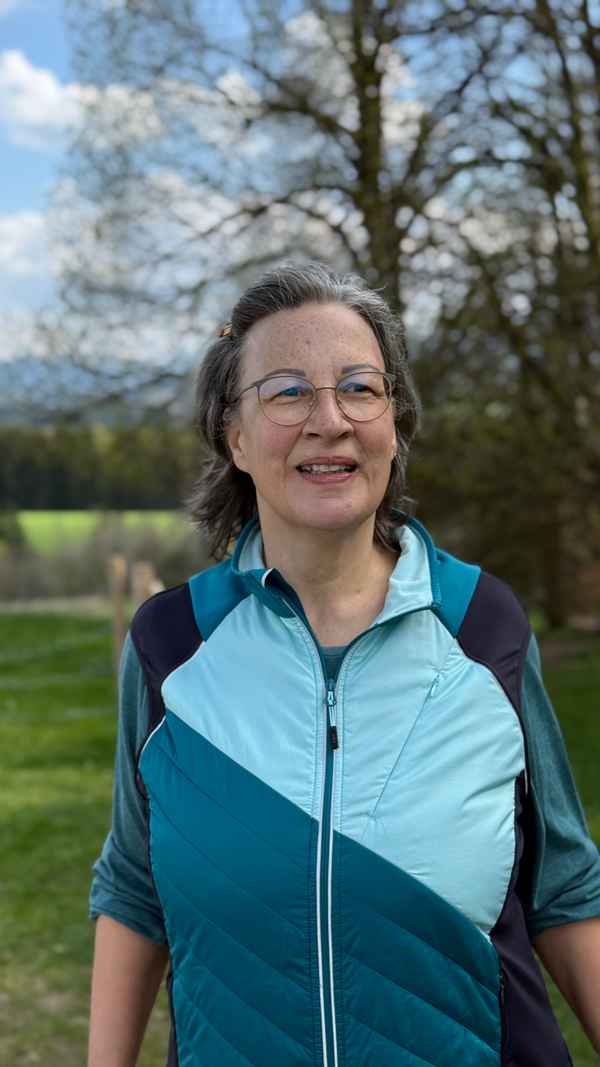 Lächelnde Frau mit Brille in Sportjacke im Frühling