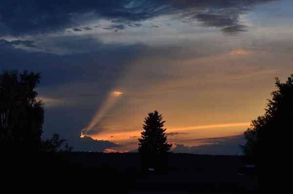 Sonnenseitenstrahl hinter Wolken beim Sonnenuntergang